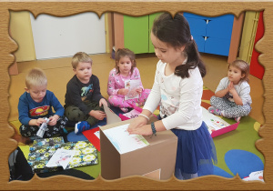 Dzieci ozdabiają pudełko swoimi rysunkami.